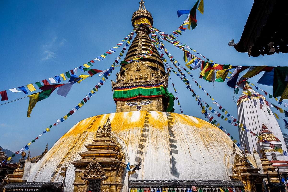white and gold buddhist stupa with Buddha's eyes painted on