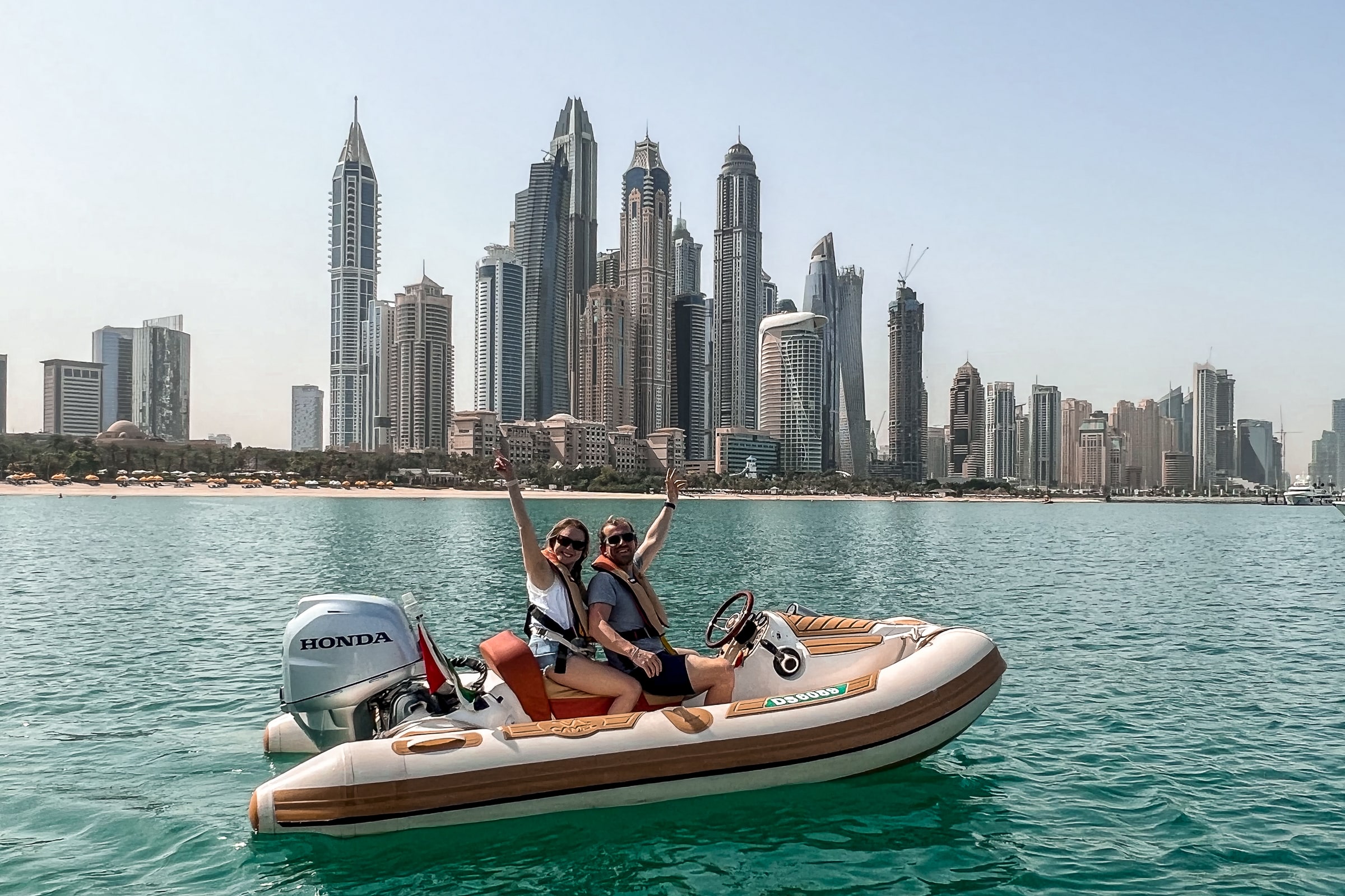 A couple on a mini speedboat in front of Dubai's skyline