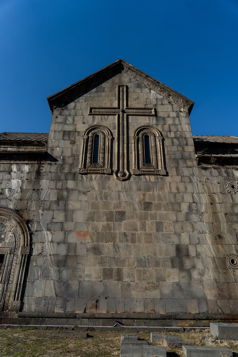A stone monastery with a large stone cross on the facade