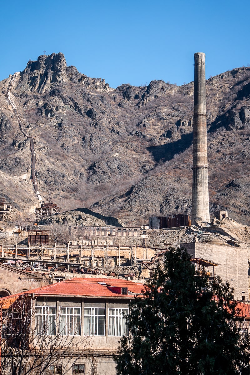 A copper mine with large chimney stack surrounded by tall mountains