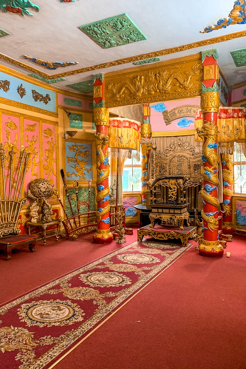 A colorful interior of a palace room with a simple throne