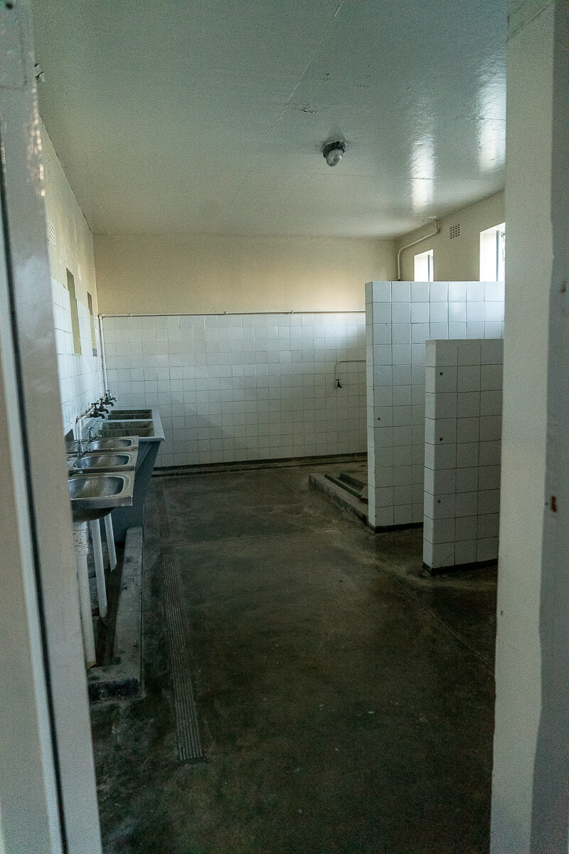 A prison bathroom with 3 sinks and walk in shower areas