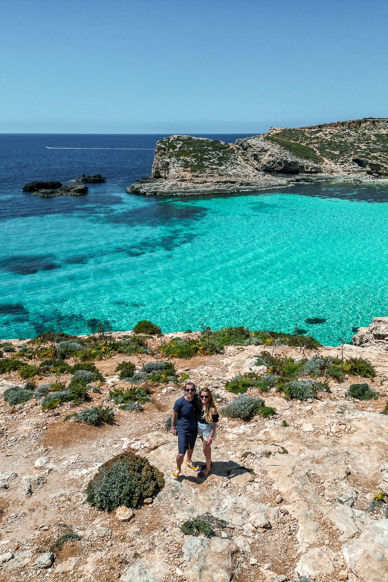An aerial view of a couple with bright blue sea and a rugged headland