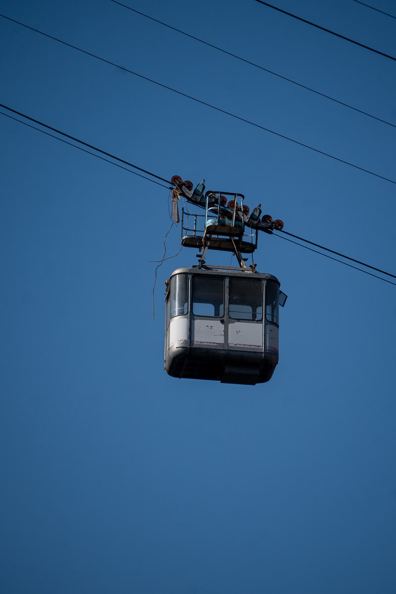 An old looking cable car dangling unused in the sky