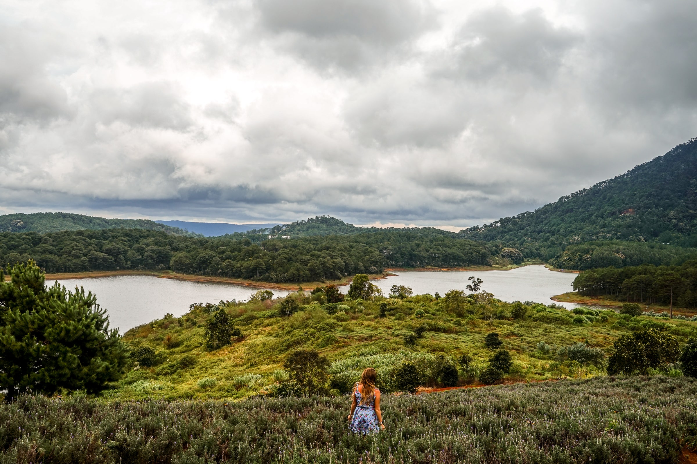 A woman overlooking a river on a grassy hillside