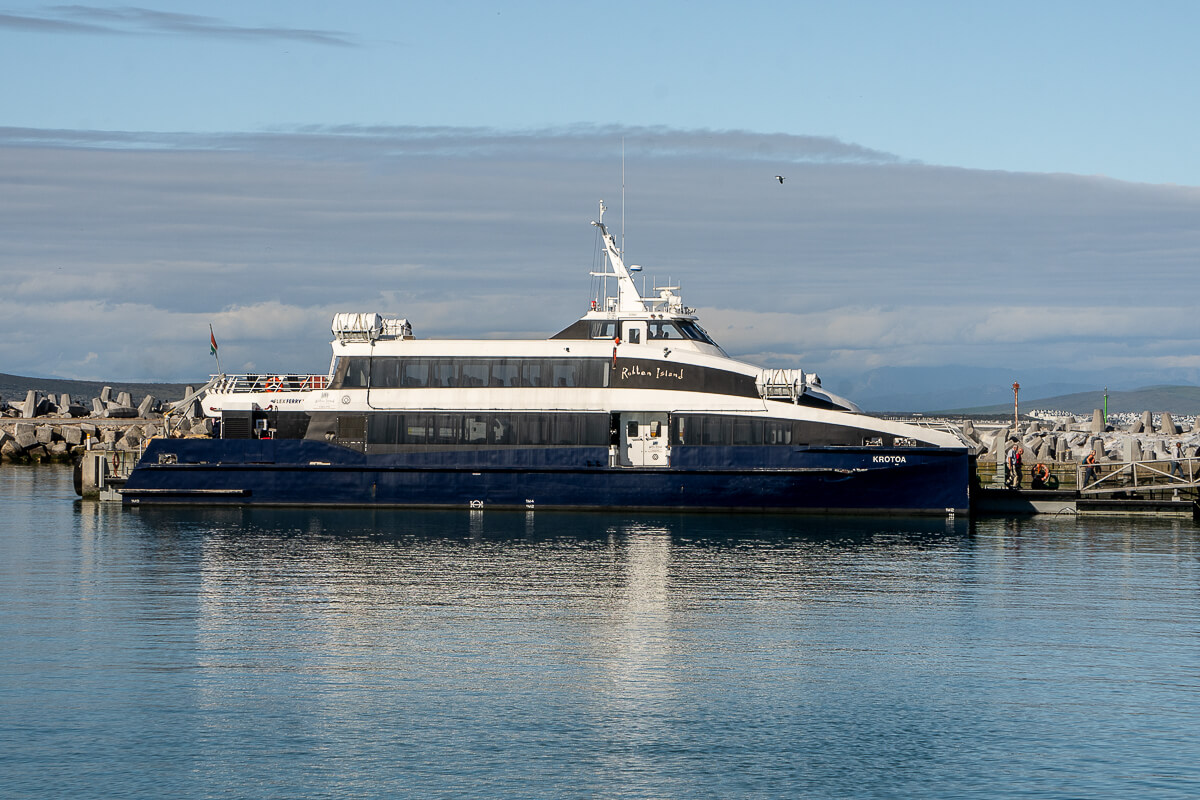 A large navy and white ferry docked at a stone breakwater