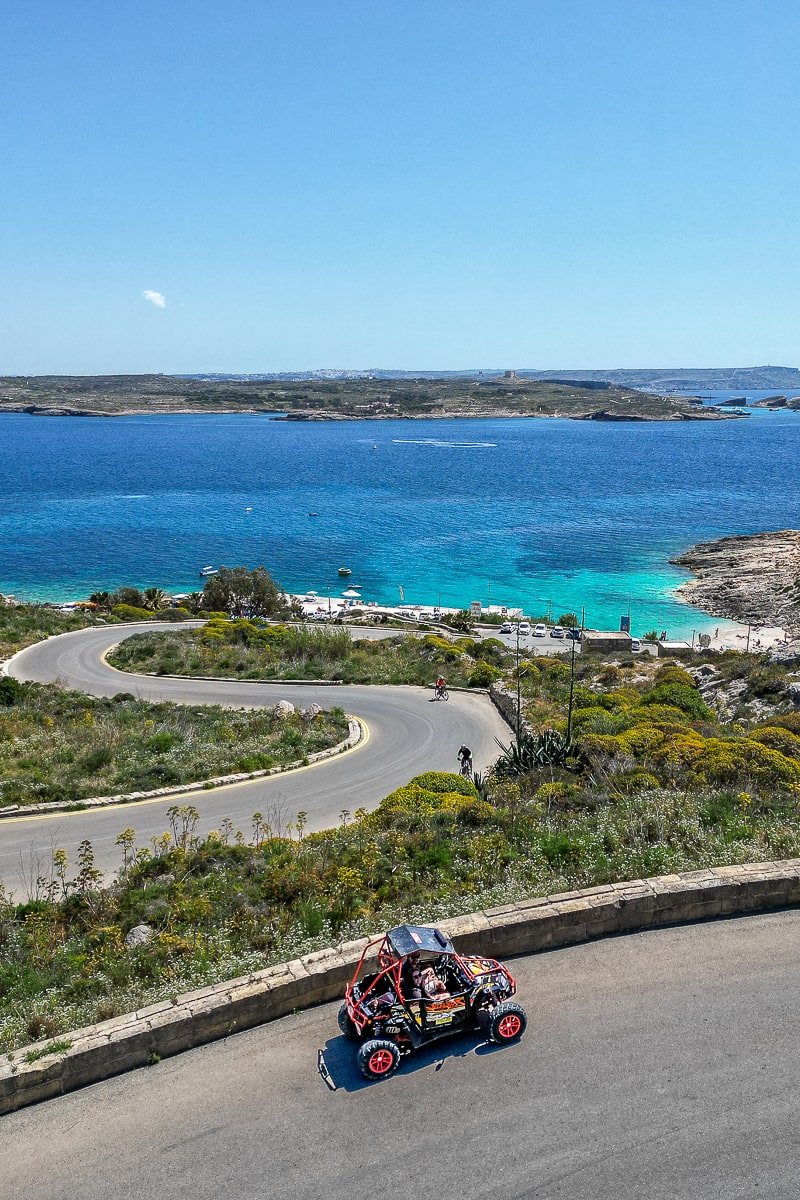 A buggy parked on a winding road with the sea behind