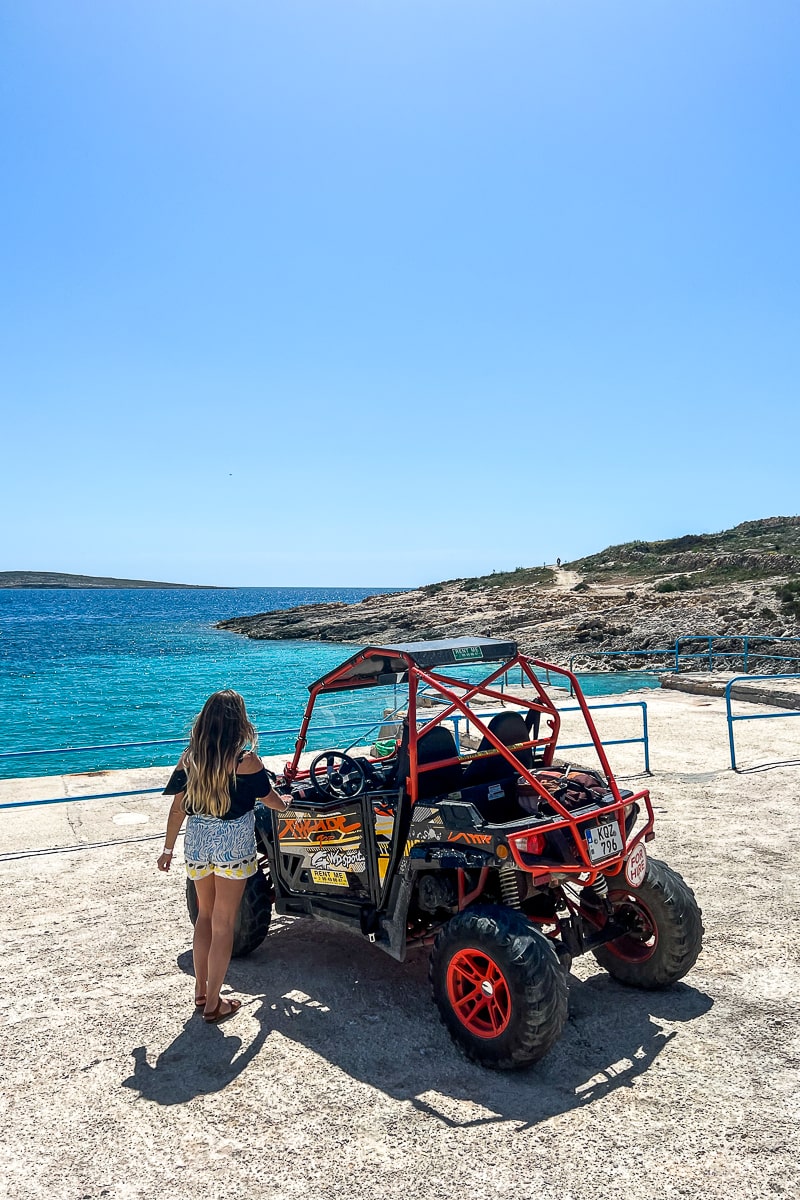 A woman approaching a small buggy parked near the sea