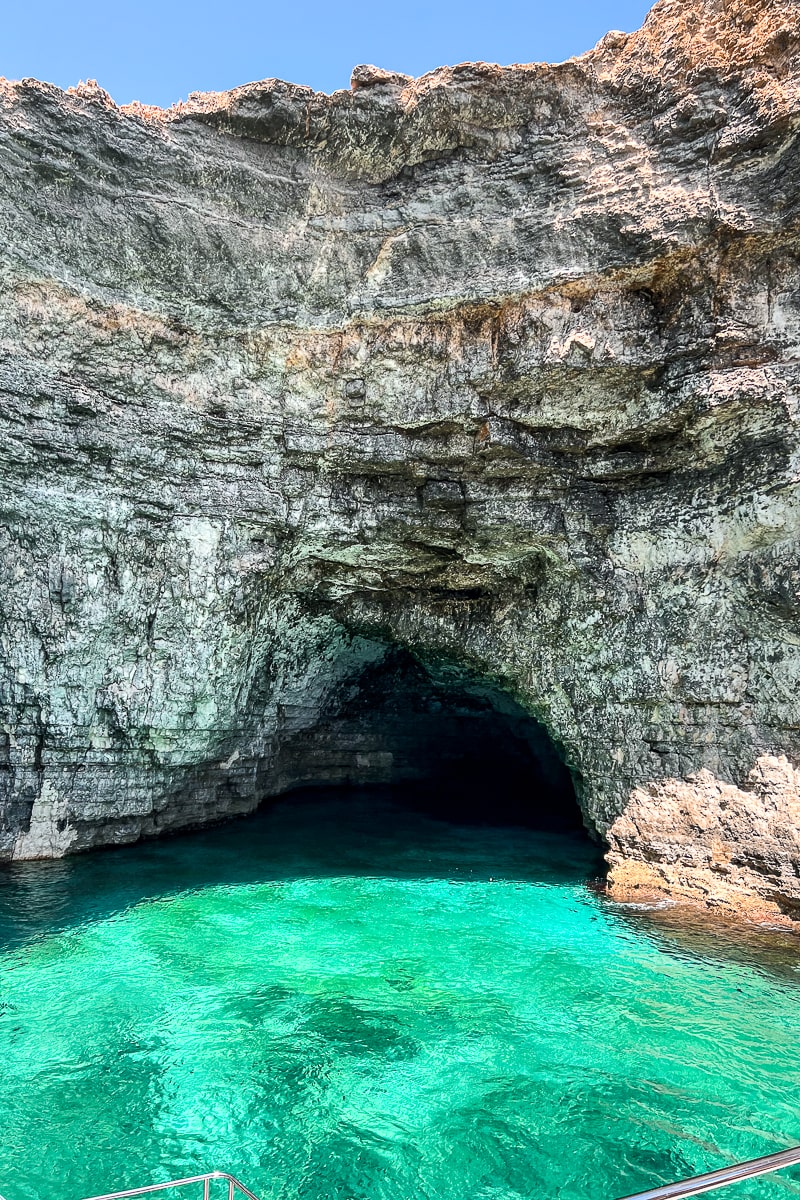 A small tidal cave on a cliff face with clear, turquoise water