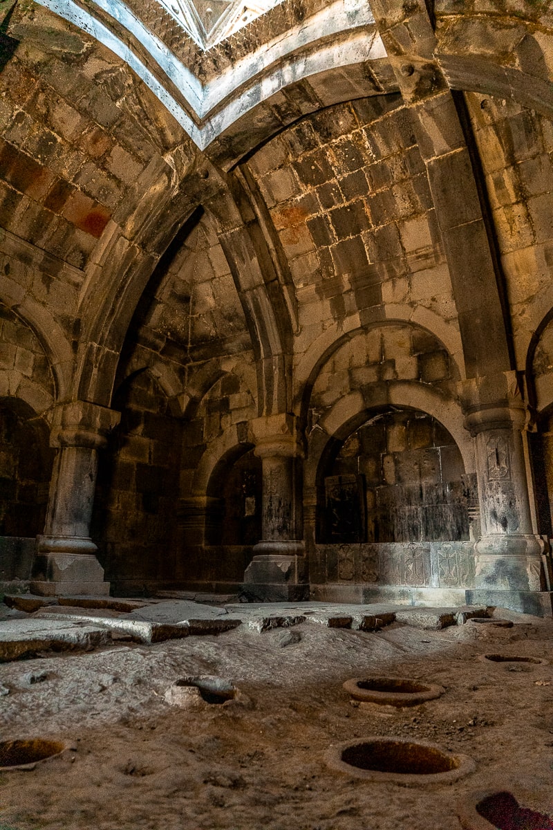 A stone room with vaulted ceilings and circular holes in the floor