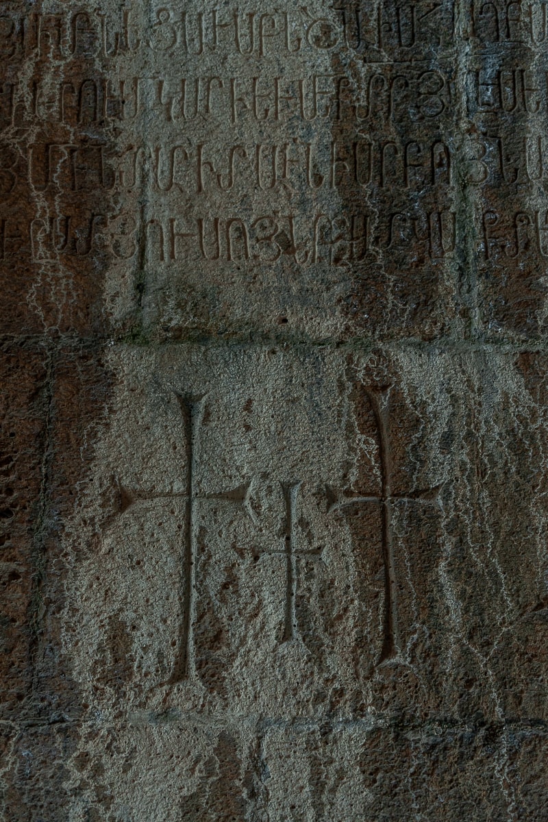 A wall engraved with three crosses and text in Armenian