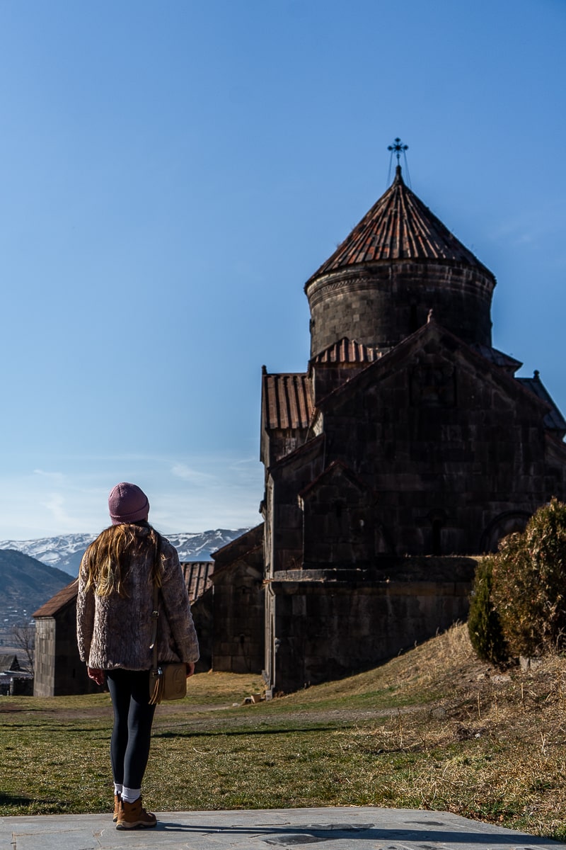A woman standing looking at a large Armenian monastery complex