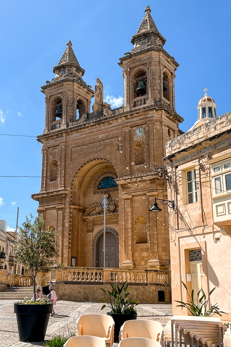 A stone colored church with double bell towers