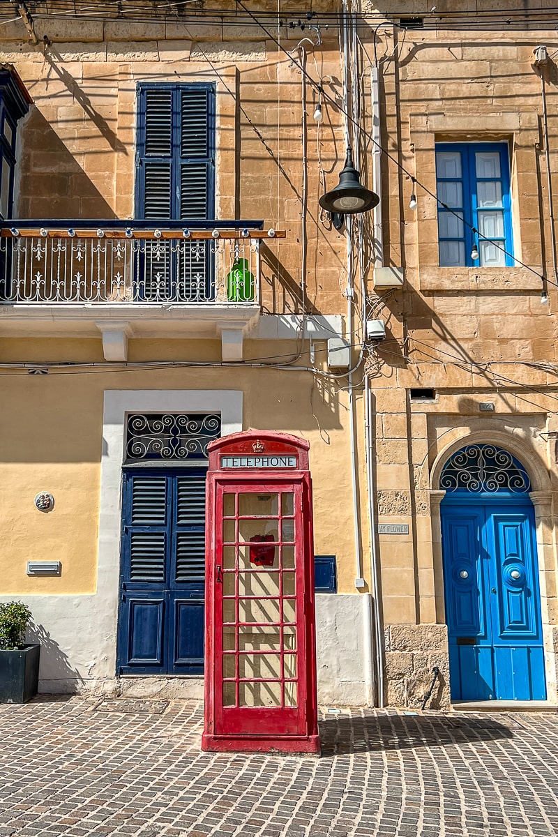 A street with bright blue wooden doors and a classic red, British telephone booth