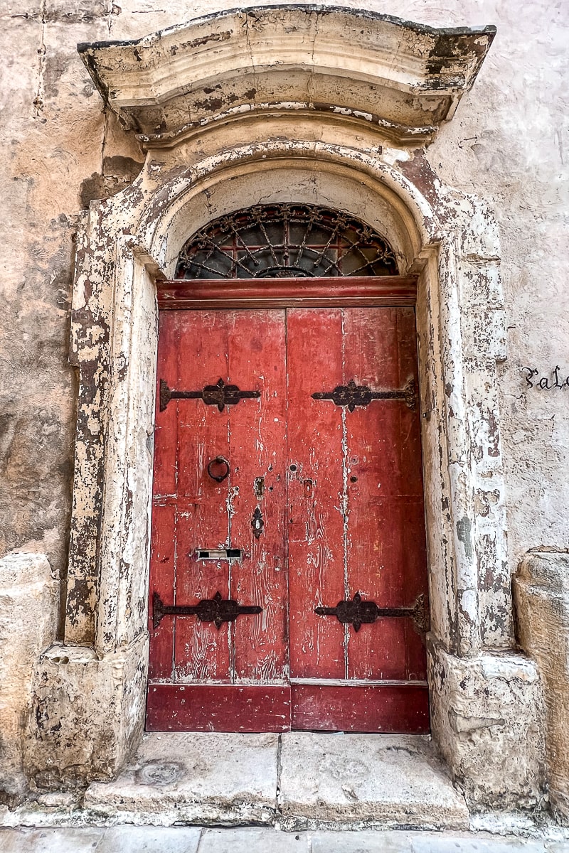 A large, red wooden door in an arched doorway