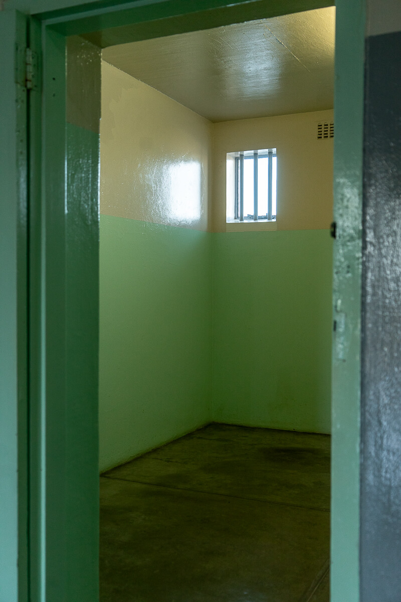 Inside a green prison cell with tiny window