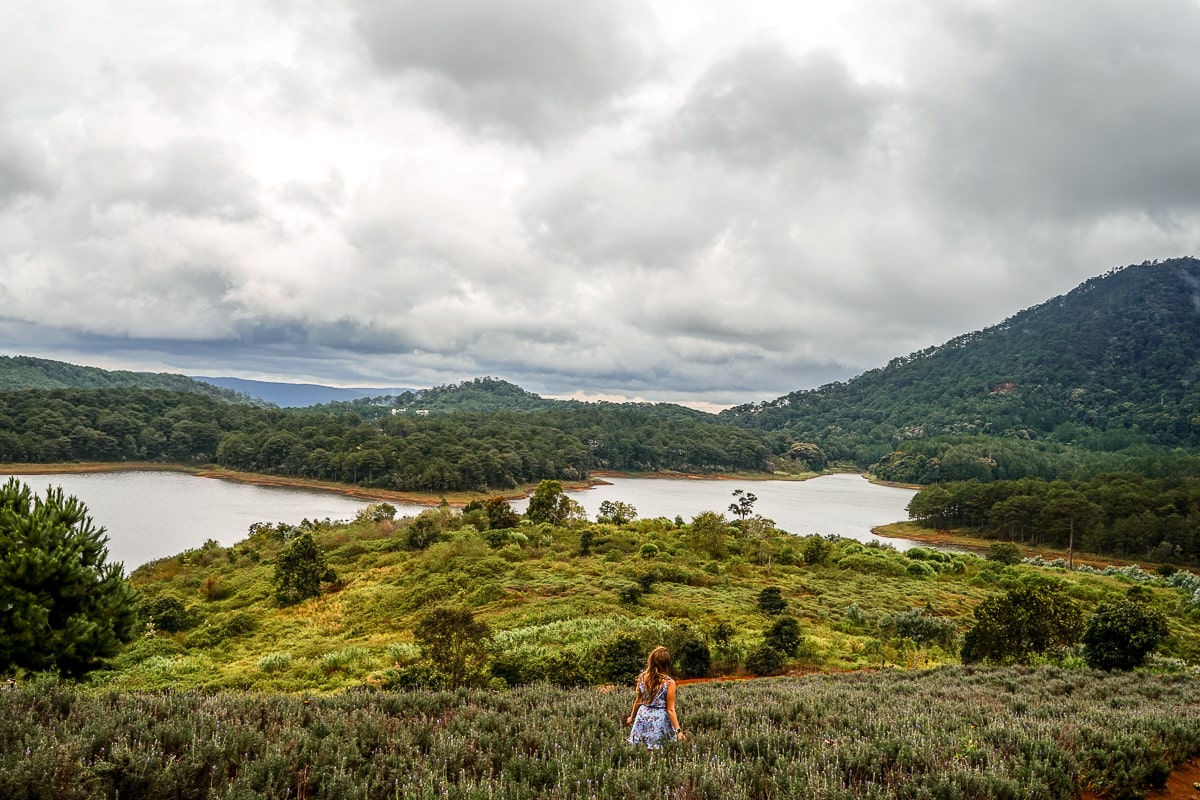 A woman walking through waist-high grass overlooking a river