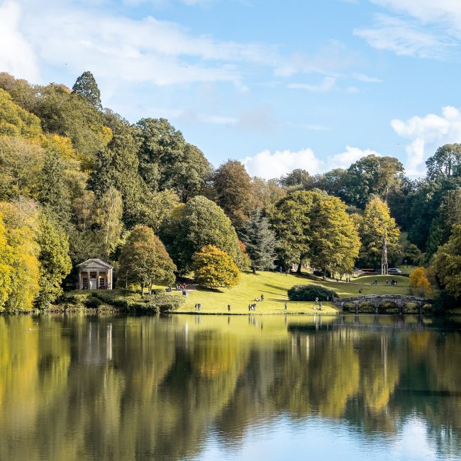 A landscape at Stourhead Gardens of the lake, Palladian bridge, and Bristol Cross - a gothic spire structure