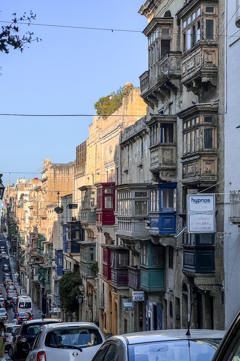 A busy street in Malta with cute, colorful wooden balconies