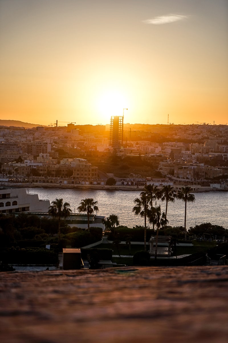 A town with half-built skyscraper with the sun setting directly behind it