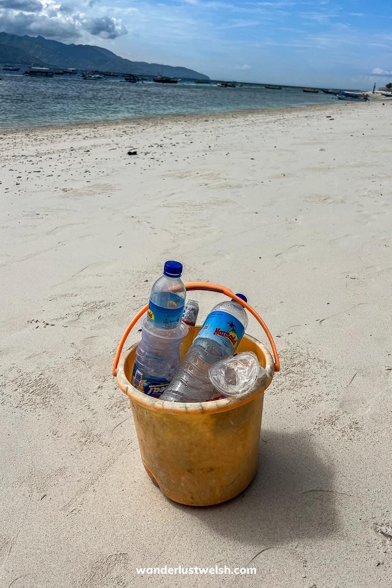 A yellow bucket on a beach filled with rubbish from a beach clean up