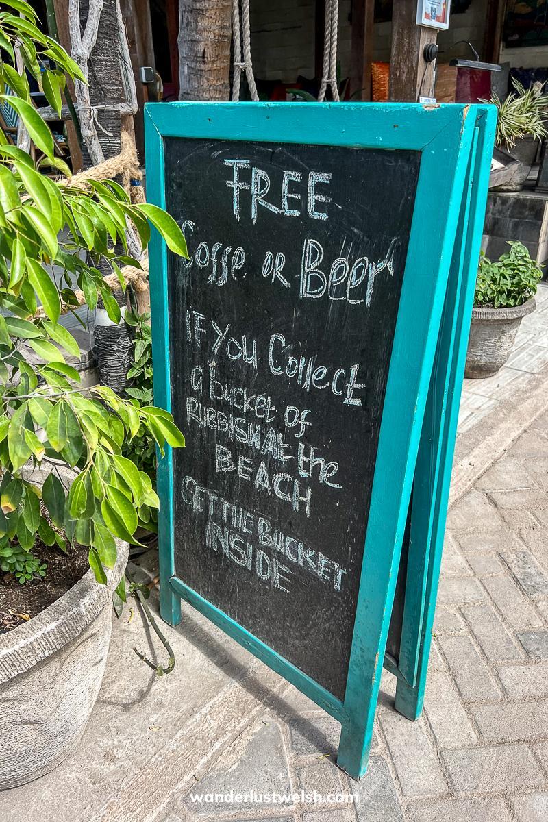 A chalkboard reading "Free coffee or beer if you collect a bucket of rubbish at the beach get the bucket inside"