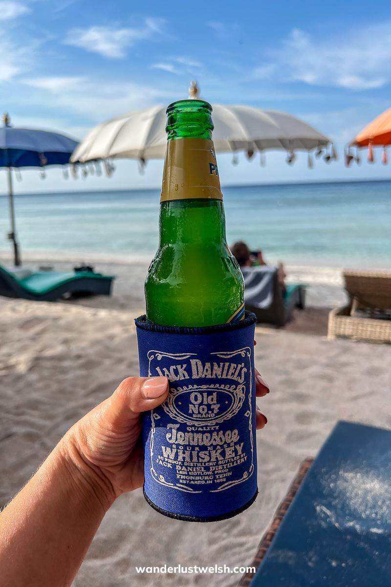 Someone holding a cold beer bottle in a foam Jack Daniels holder