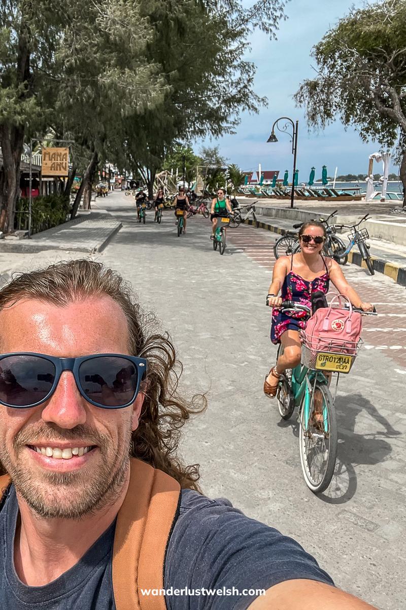 Selfie of a couple riding green rental bikes on a stone paved road