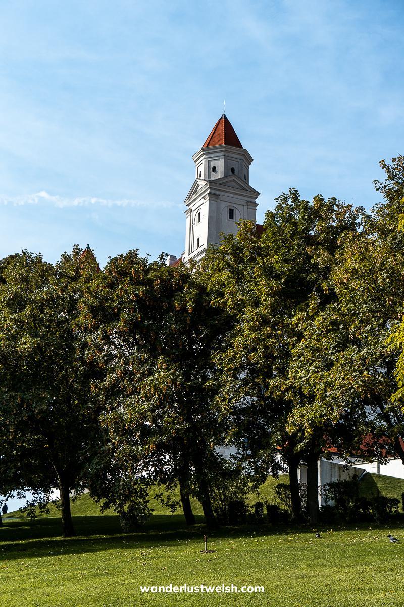 A tower of Bratislava castle poking above large trees