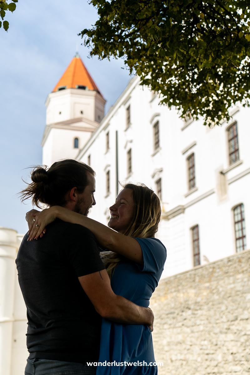 A couple embracing in front of Bratislava castle with an overhanging tree