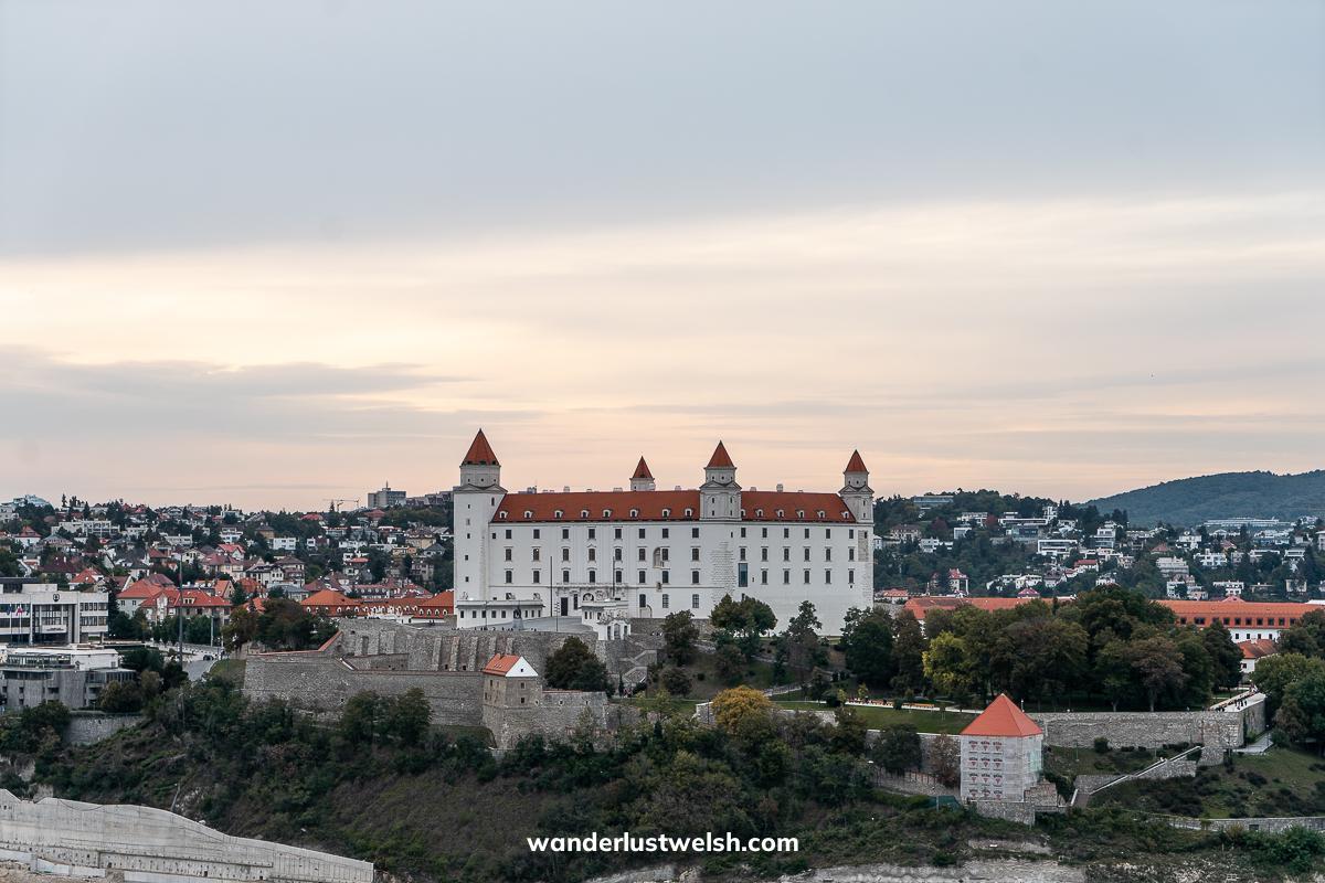A wide view of Bratislava castle - a modern looking white castle with orange roof and four small corner towers