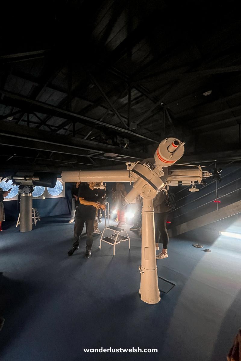 A man giving a talk surrounded by a set of large telescopes