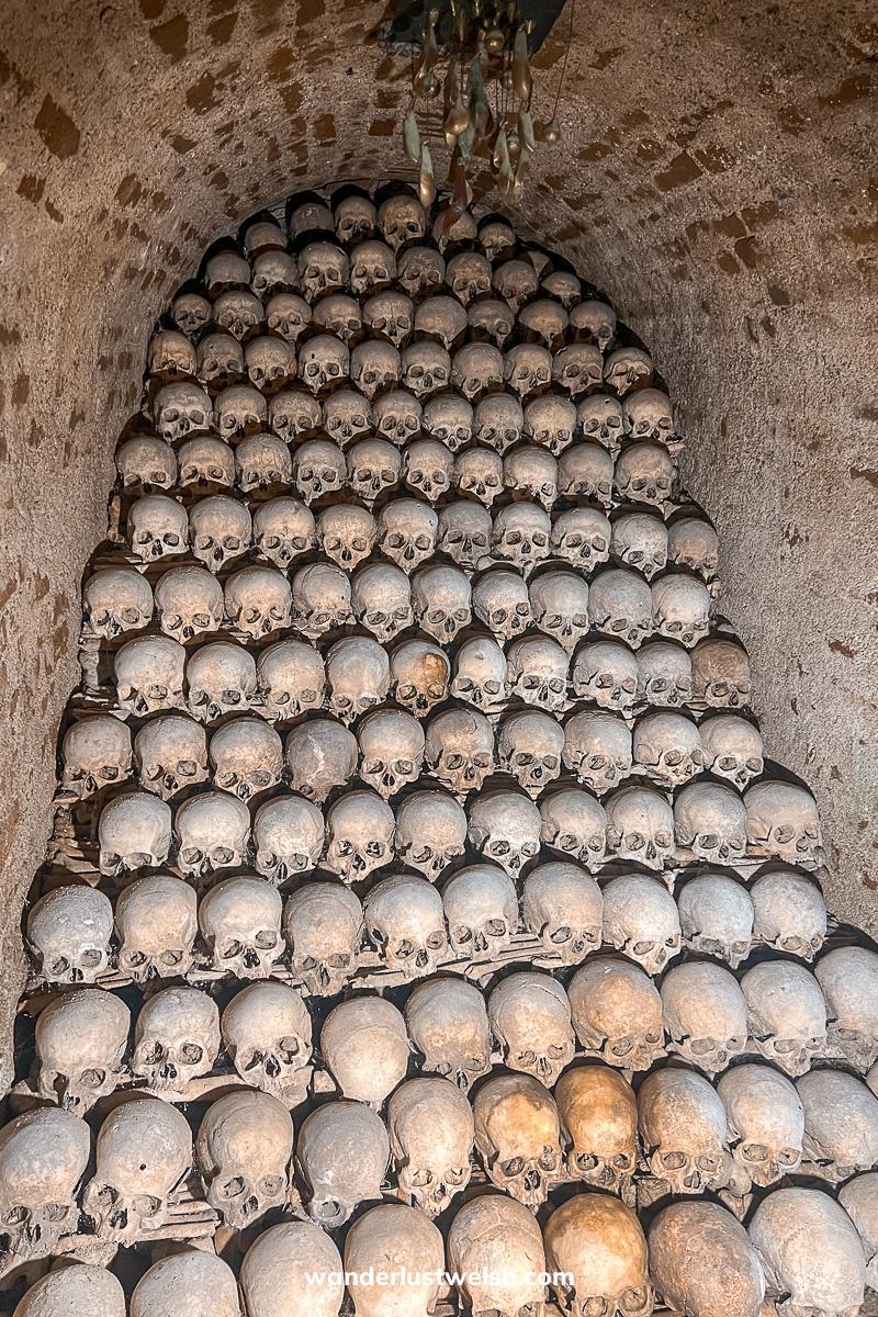 A sloping wall of human skulls in an underground ossuary