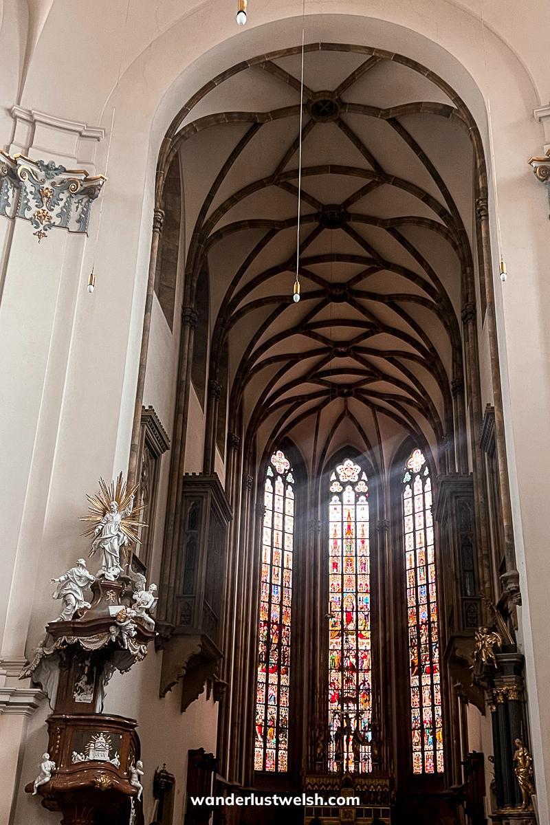 A large stained glass window with detailed vaulted ceiling above