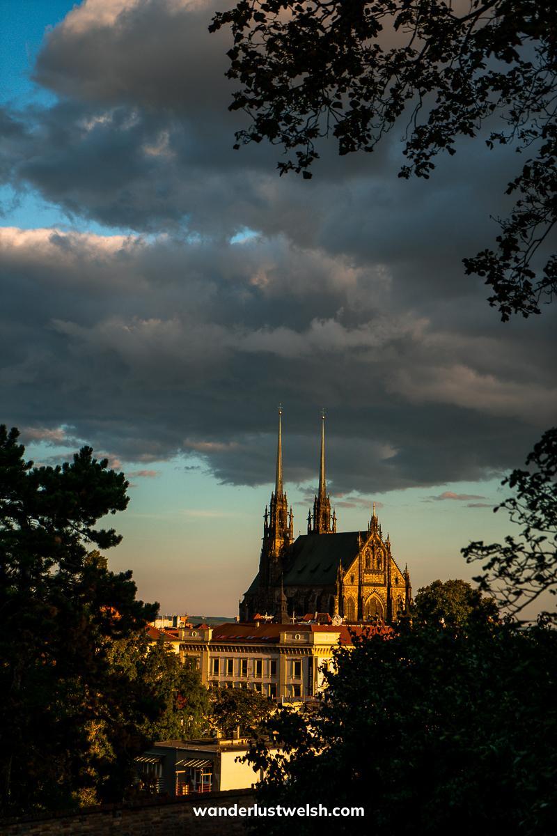A double spired church at sunset framed by trees