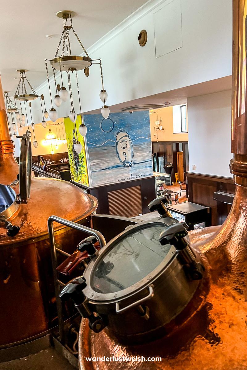 Copper brewing vats in a modern pub with colorful artwork on the walls