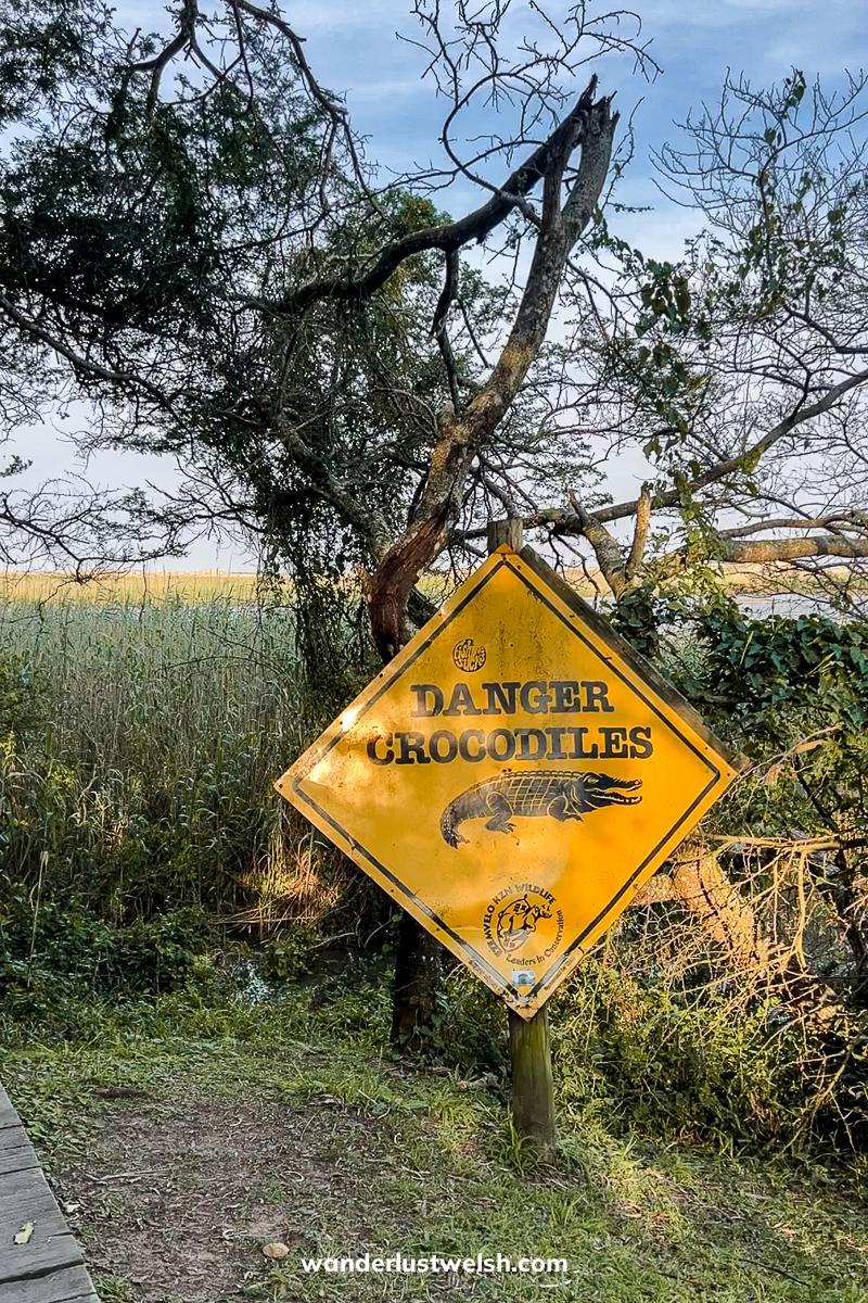 A yellow diamond sign reading "Danger crocodiles" and an image of a crocodile