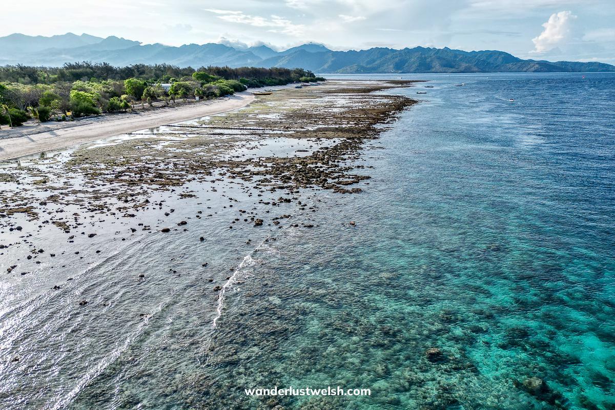 Aerial view of rocky, coral shoreline and sea on the Gilis