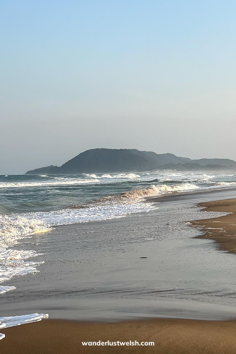 Frothy waves landing on a sandy shore before sunset