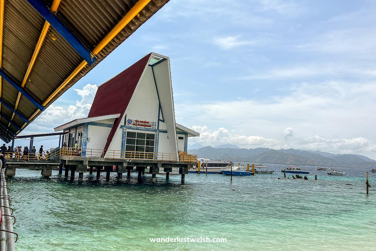 A tall ferry port building on a wooden pier in the sea