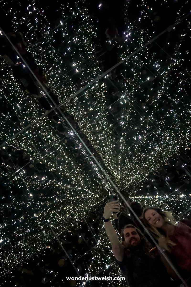 A couple in a reflective floor which looks like it's in space - black background with thousands of white stars