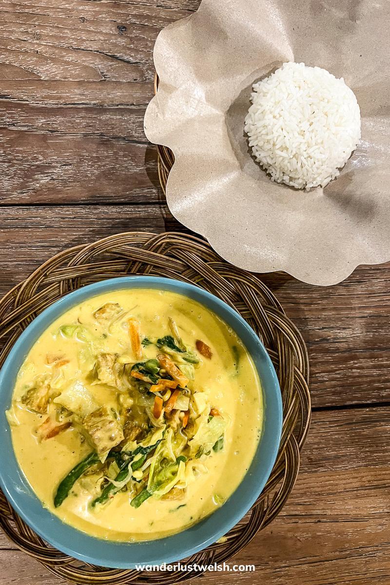 A top down view of a yellow curry and rice on a wooden table