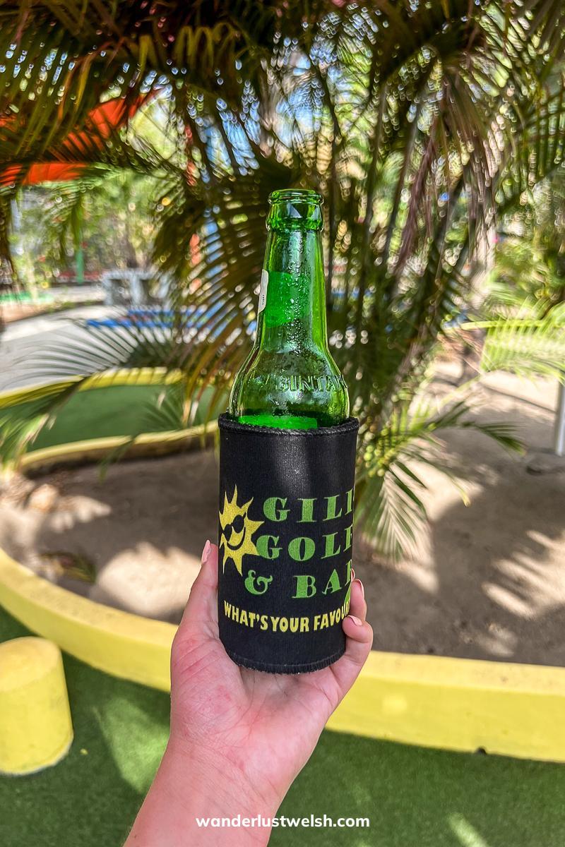 Someone holding a beer with "Gili Golf & Bar" written on it