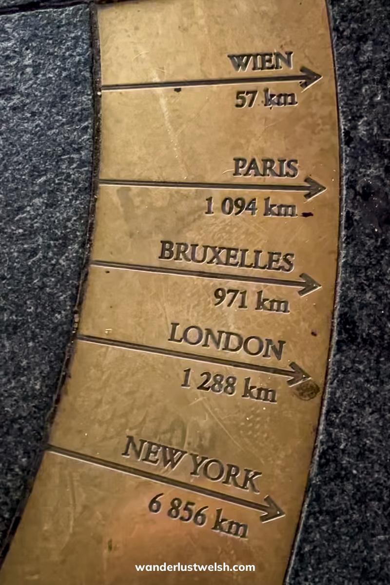 A bronze sculpture carved with distances to Vienna (57 km), Paris (1,094 km), Brussels (971 km), London (1,288 km), and New York (6,856 km)