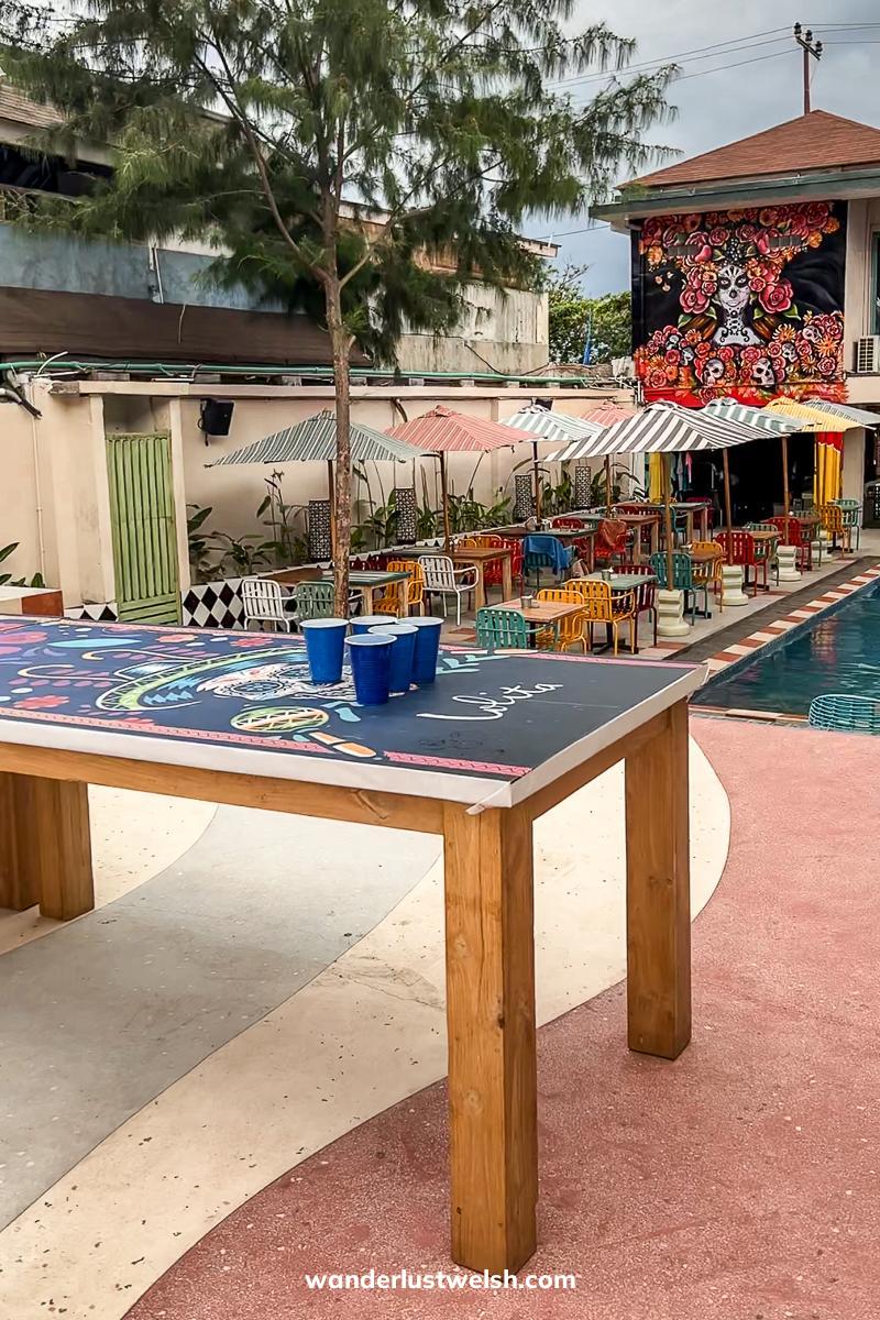 A table with beer pong set up on it with tables and a pool behind
