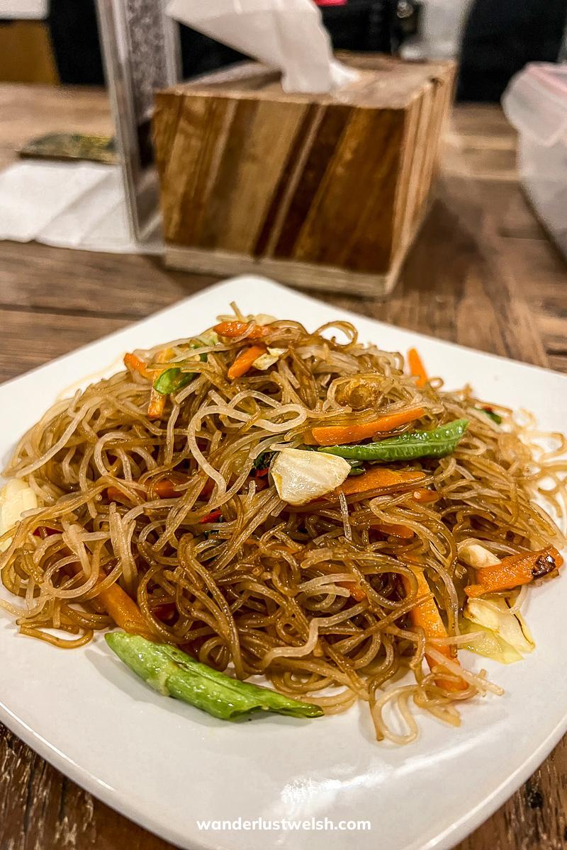A plate of mie goreng - fried noodles with vegetables - on a square, white plate