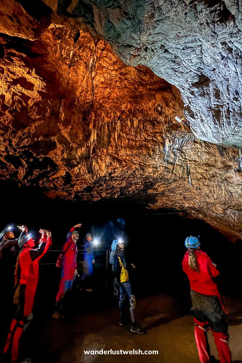 A group of people in boiler suits and hardhats admiring the inside of a cave