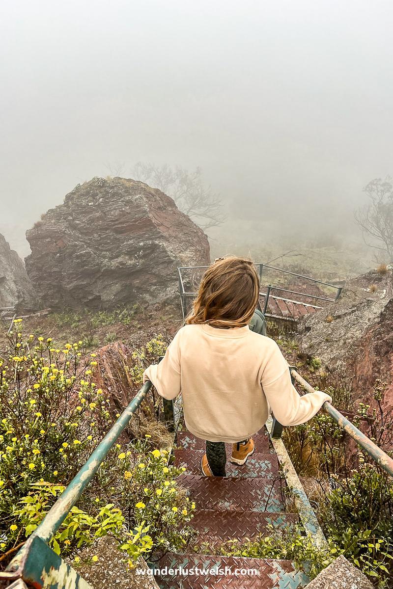A woman descending steep steps towards an iron mine