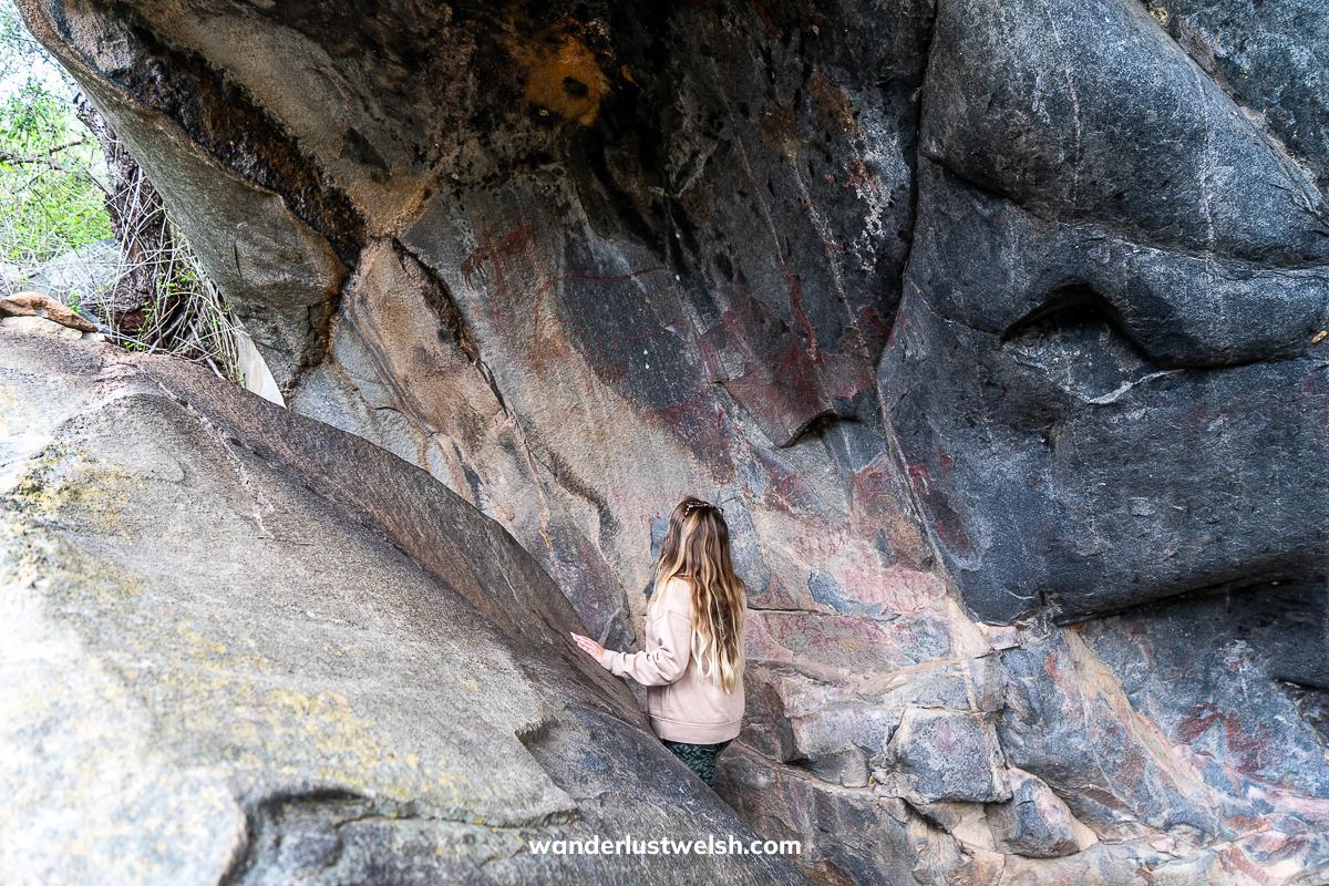 A woman looking at red cave paintings in Eswatini
