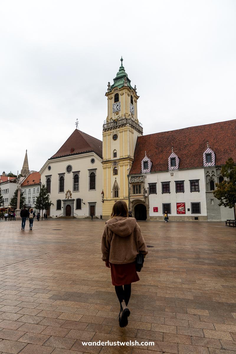 A woman walking towards the old town hall in Bratislava